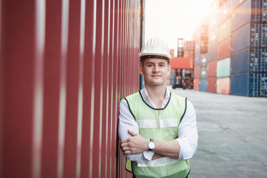 portrait-of-a-worker-standing-in-container-shipyard-free-photo
